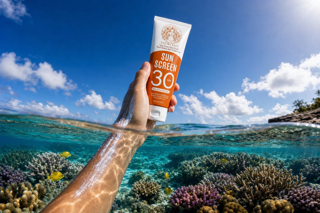 Snorkeler holding the Eat My Face SPF 30 reef-safe non-nano zinc sunscreen tube above a healthy coral reef — over-under split-level photograph showing visible non-nano zinc on hand.