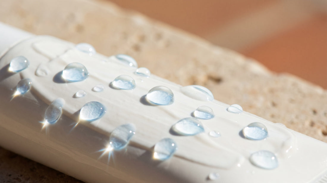 Water droplets beading and rolling off skin coated in white mineral sunscreen