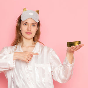 beef tallow nighttime face cream with lavender and chamomile in jar held by woman in satin pajamas and sleep mask on pink background